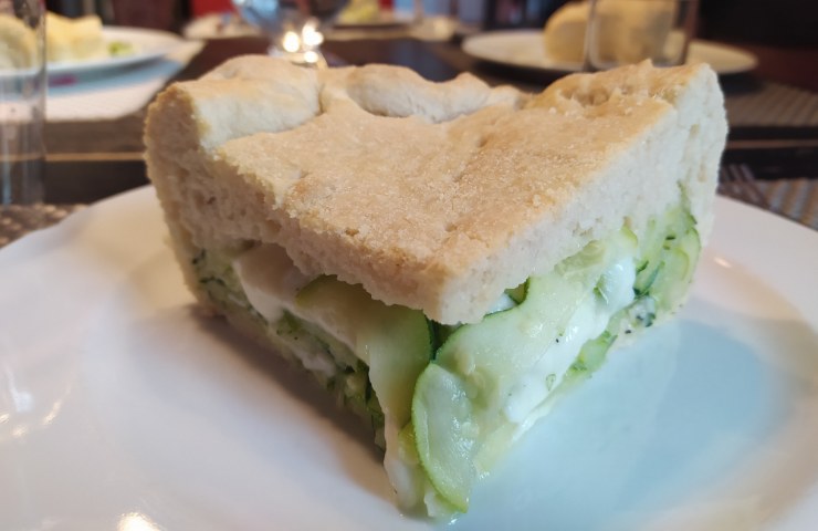 Una fetta di focaccia ripiena di mozzarella e zucchine