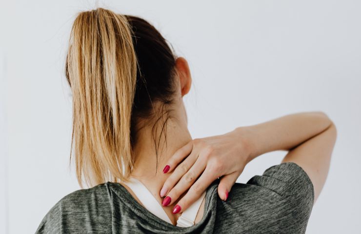 Una ragazza di spalle col mal di collo