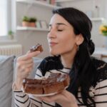donna con in mano un pezzo di torta al cioccolato