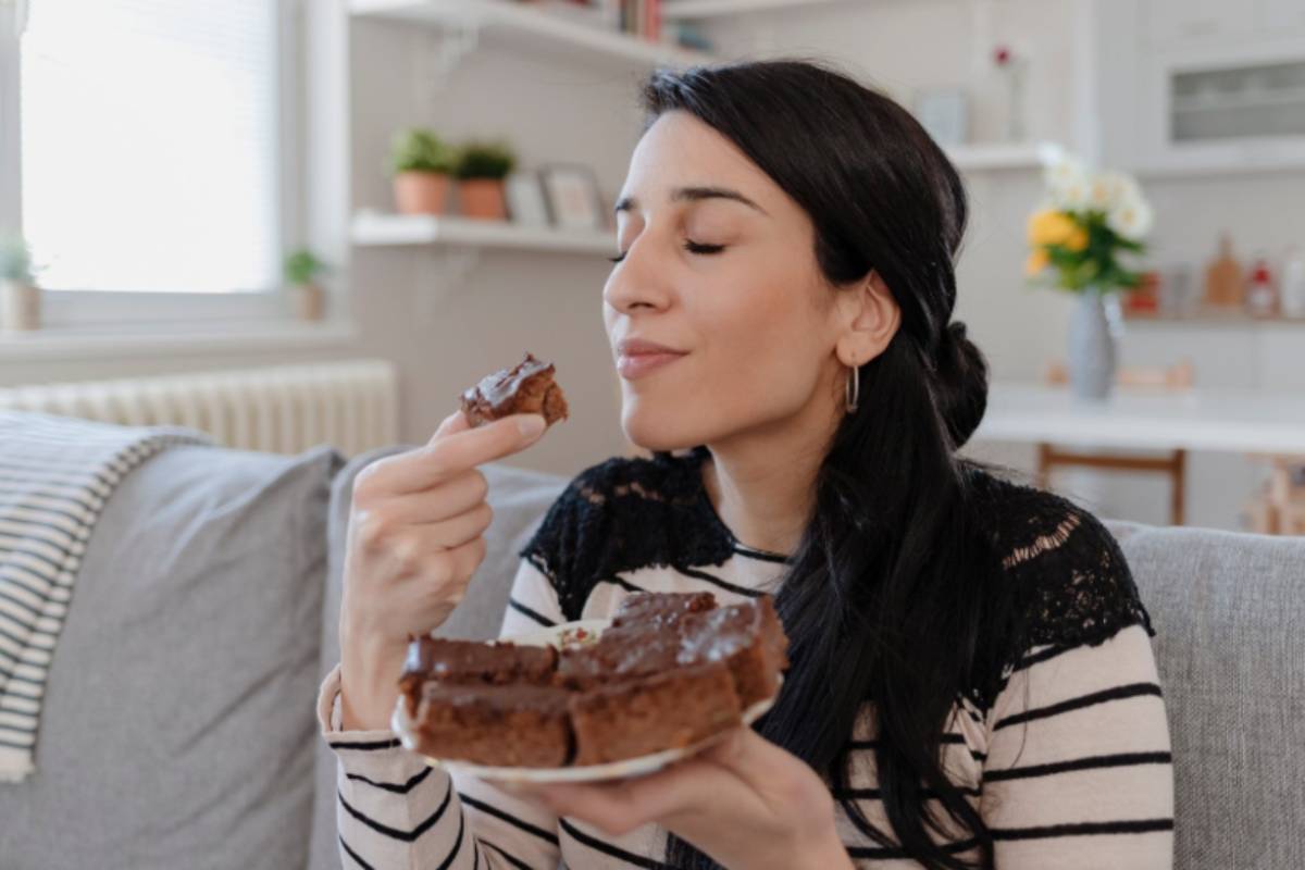 donna con in mano un pezzo di torta al cioccolato